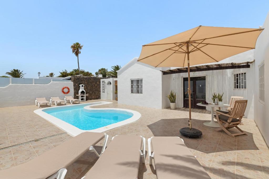 un patio avec un parasol et une piscine dans l'établissement Casa Keiley by EscapeHome, à Puerto del Carmen