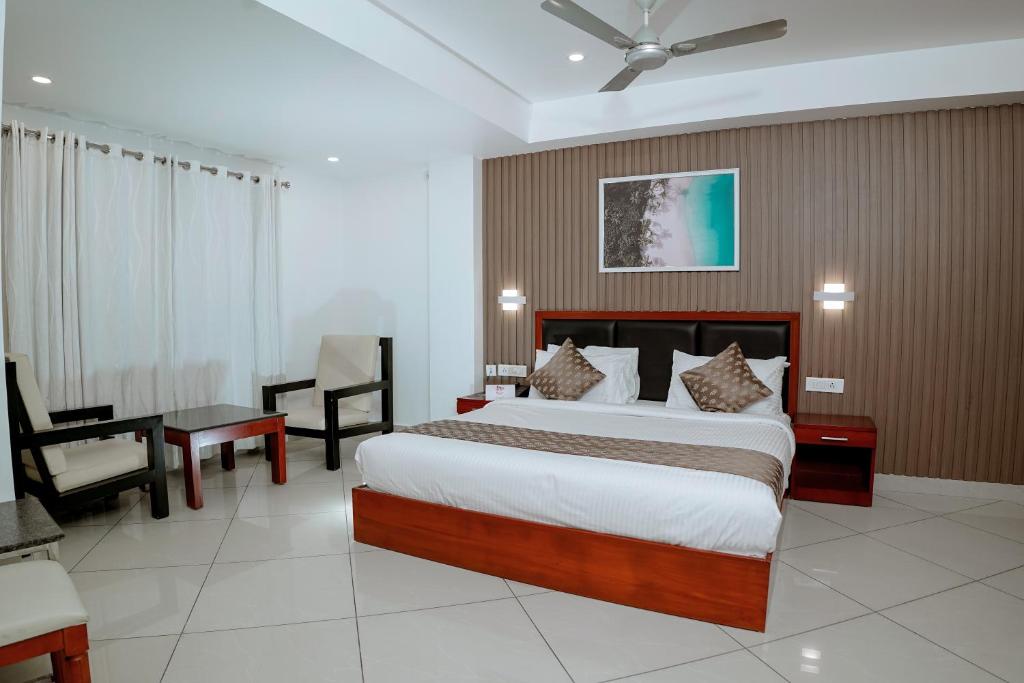 a bedroom with a bed and a desk and a chair at Queens Hotel in Kozhikode