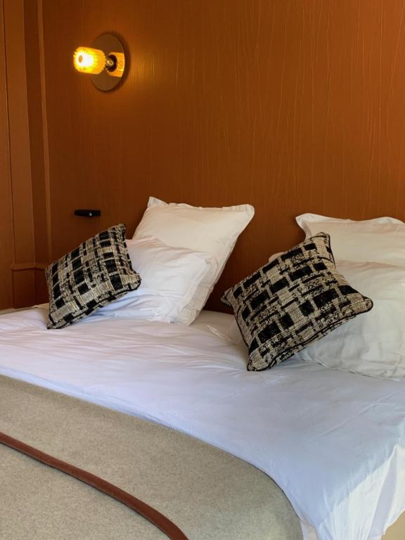 Una cama con tres almohadas encima. en Le Prieuré d'Arbois, en Arbois