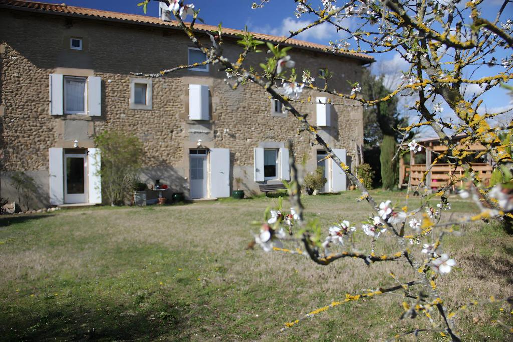 a large stone house with white doors and a yard at Gîte La Ferme De Musan in Chatuzange-le-Goubet