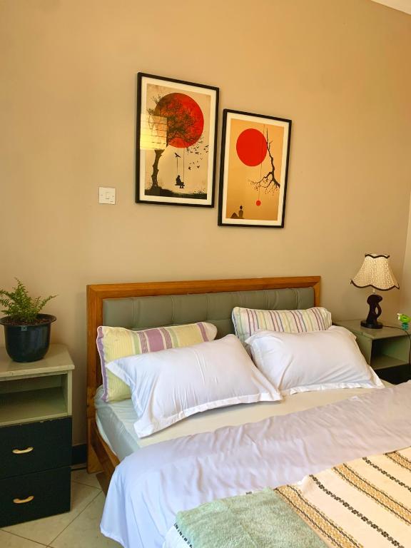 two beds in a bedroom with two pictures on the wall at Angello Apartment in Kira