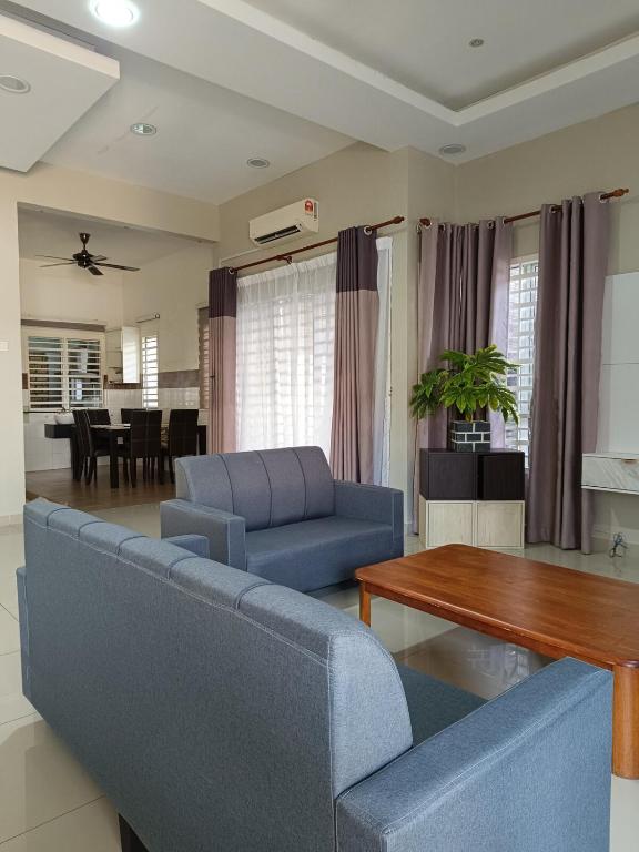 a living room with a blue couch and a table at Ateh's Homestay KLIA1 in Sepang