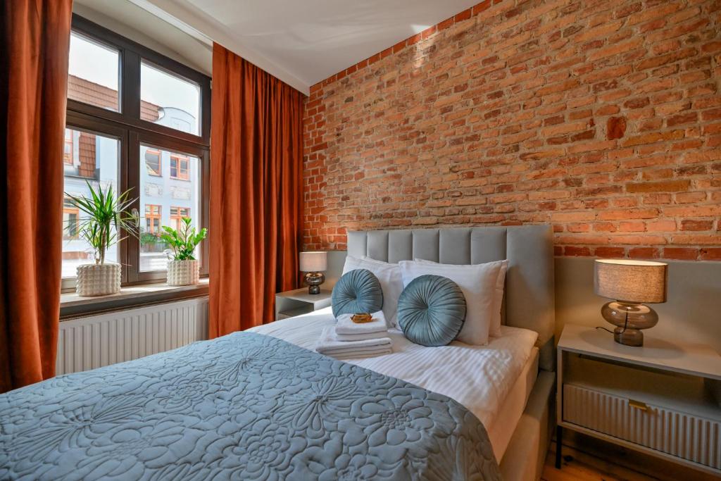 a bedroom with a brick wall and a bed at Szeroka Residences in Toruń