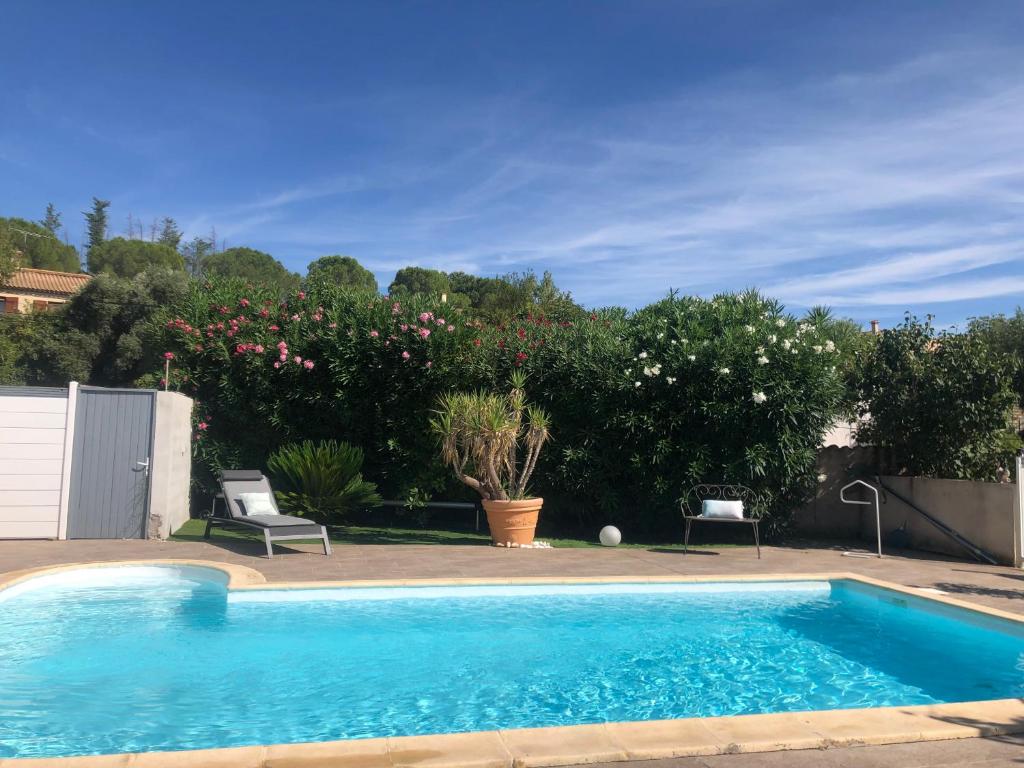 a blue swimming pool with two chairs and trees at Villa Bel Air in Puisserguier