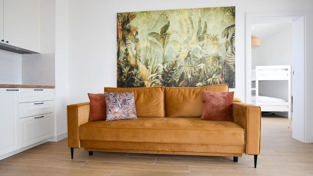 a couch in a living room with a painting on the wall at VacationClub - Słoneczne Osiedle Apartament 17 in Ustronie Morskie