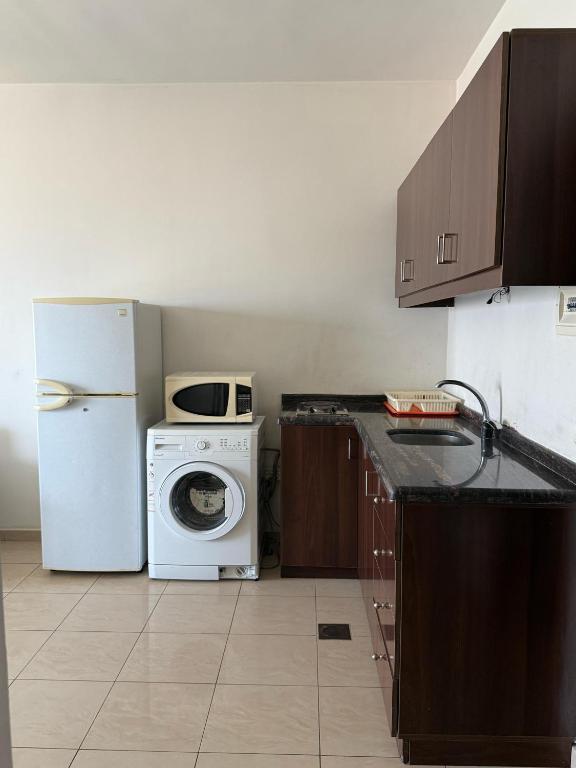 a kitchen with a washing machine and a refrigerator at Laforge Residence in Al Bāţiyah