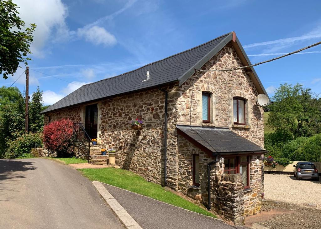 una casa in pietra sul lato di una strada di Riscombe Farm Cottages a Exford