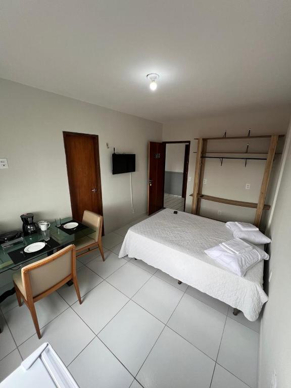 a bedroom with a bed and a table and a desk at Residencial Sol - Cidade alta in Natal