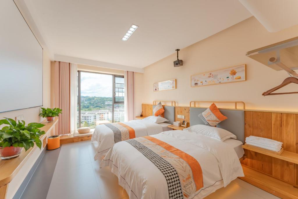 two beds in a room with a window at Huimu Mansion - Tianmenshan Branch-free pick-up in Xixiping