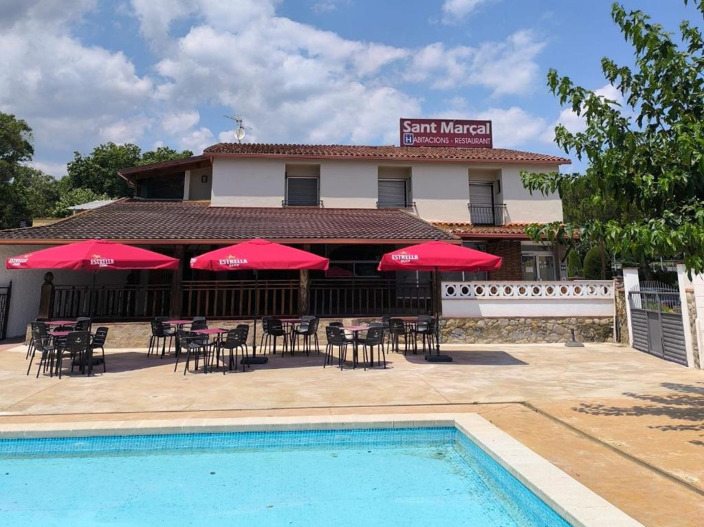 a restaurant with tables and chairs and red umbrellas at Hostal Restaurant Sant Marçal in Amer