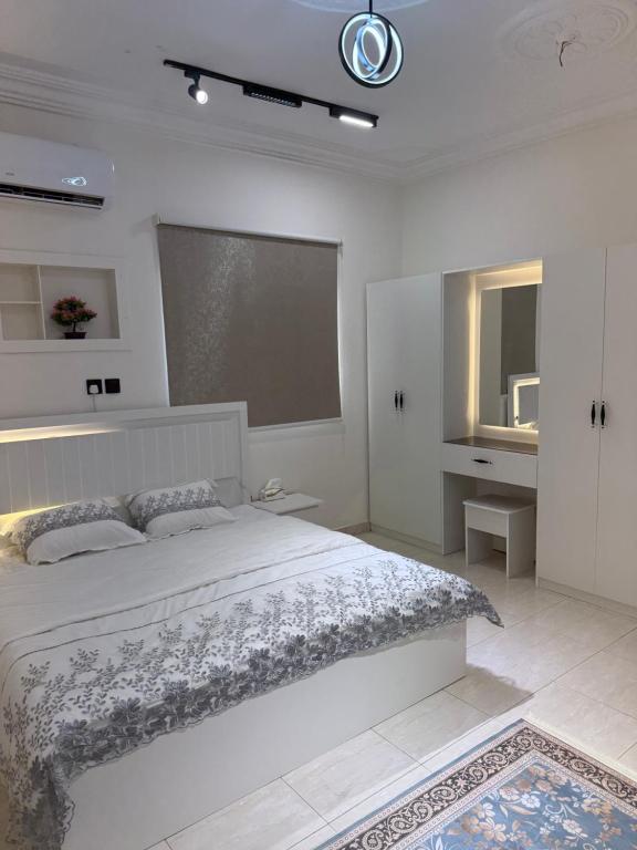 a white bedroom with a large bed and a window at قصر الضيافه in Al Madinah