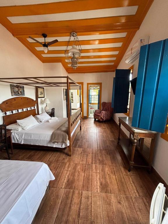 a bedroom with two beds and a desk in it at Suítes Casa da Colônia in Paraty