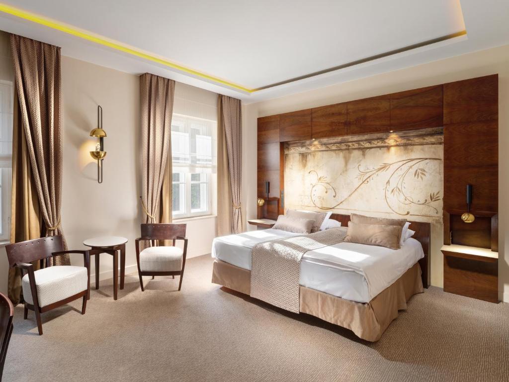 a bedroom with a bed and a table and chairs at Mamaison Le Regina Boutique Hotel in Warsaw