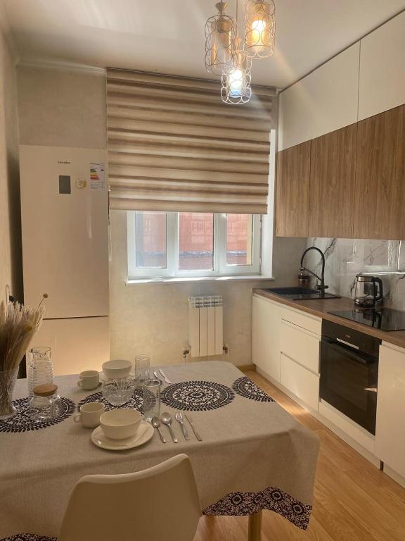 a kitchen with a table with plates on it at 2 комнатная квартира золотой квадрат ЖК Москва in Astana
