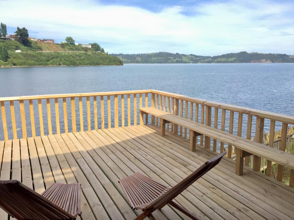 a deck with two chairs and a bench on the water at Palafito Azul Apart Hotel in Castro