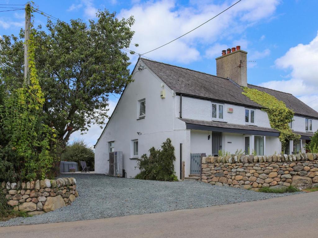 ein weißes Cottage mit einer Steinmauer in der Unterkunft Pencefn Cottage in Llanddeiniolen