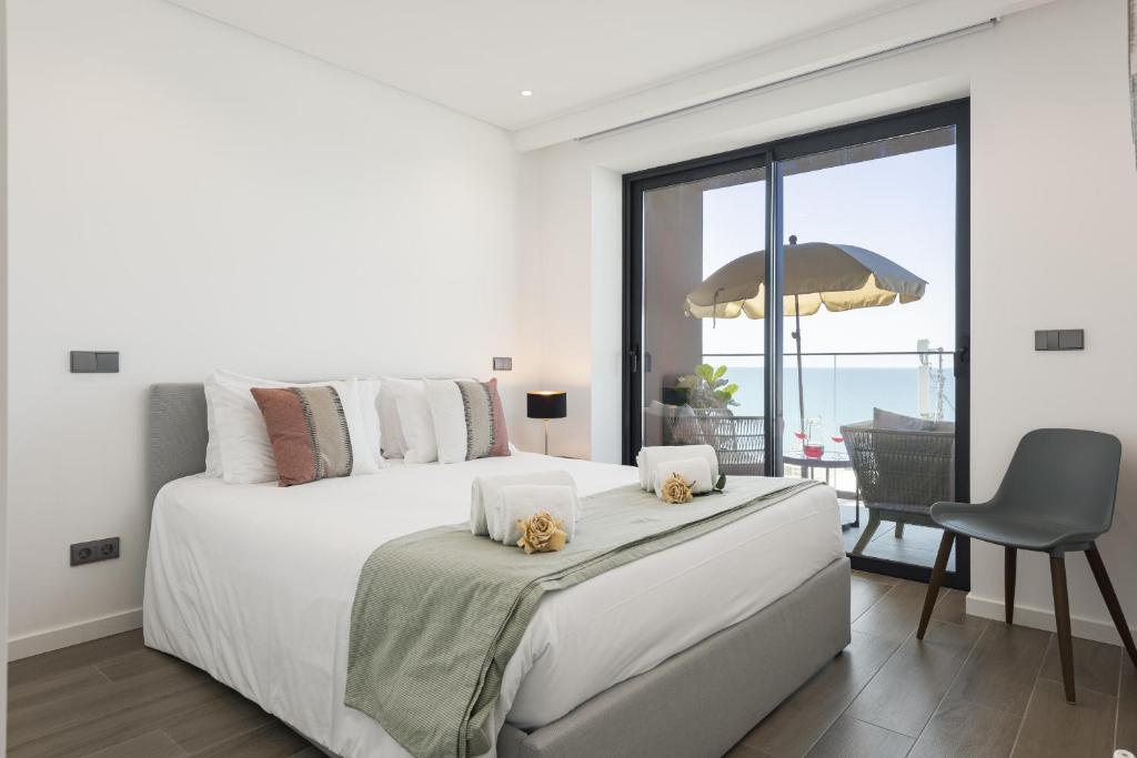 a white bedroom with a bed and a view of the ocean at Terracos de Quarteira II Cherry by Real Properties in Cavacos