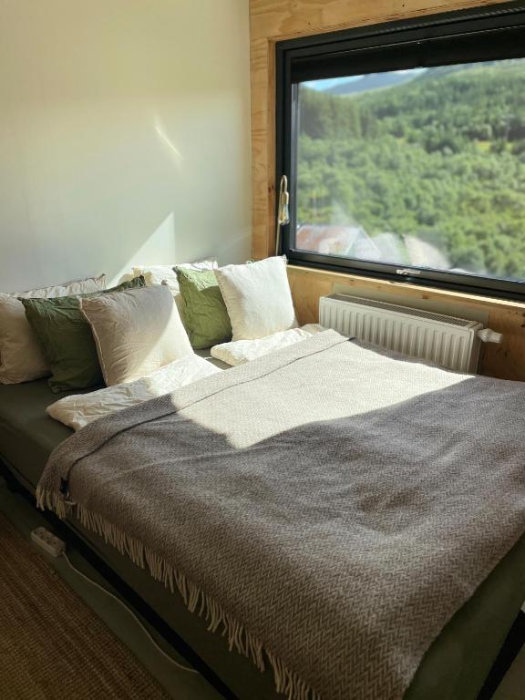 a bed in a room with a large window at Nykmark - Eco House - Room Selva in Bøstad