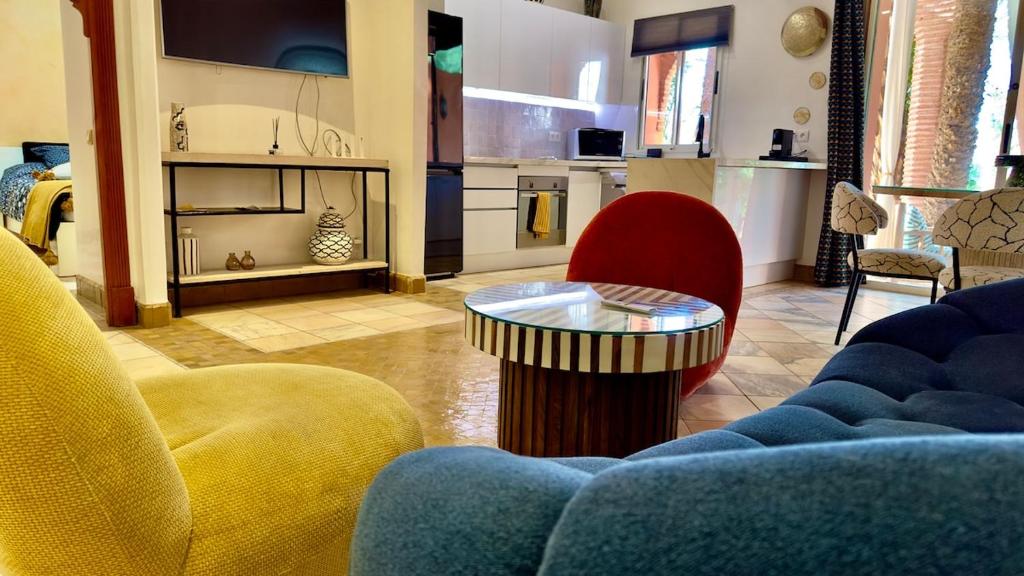 ein Wohnzimmer mit Couch und Tisch und eine Küche in der Unterkunft Appart villa de luxe avec 5 piscines in Marrakesch
