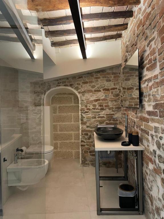 a bathroom with a sink and a toilet in a brick wall at La Scalinata Suite in Perugia