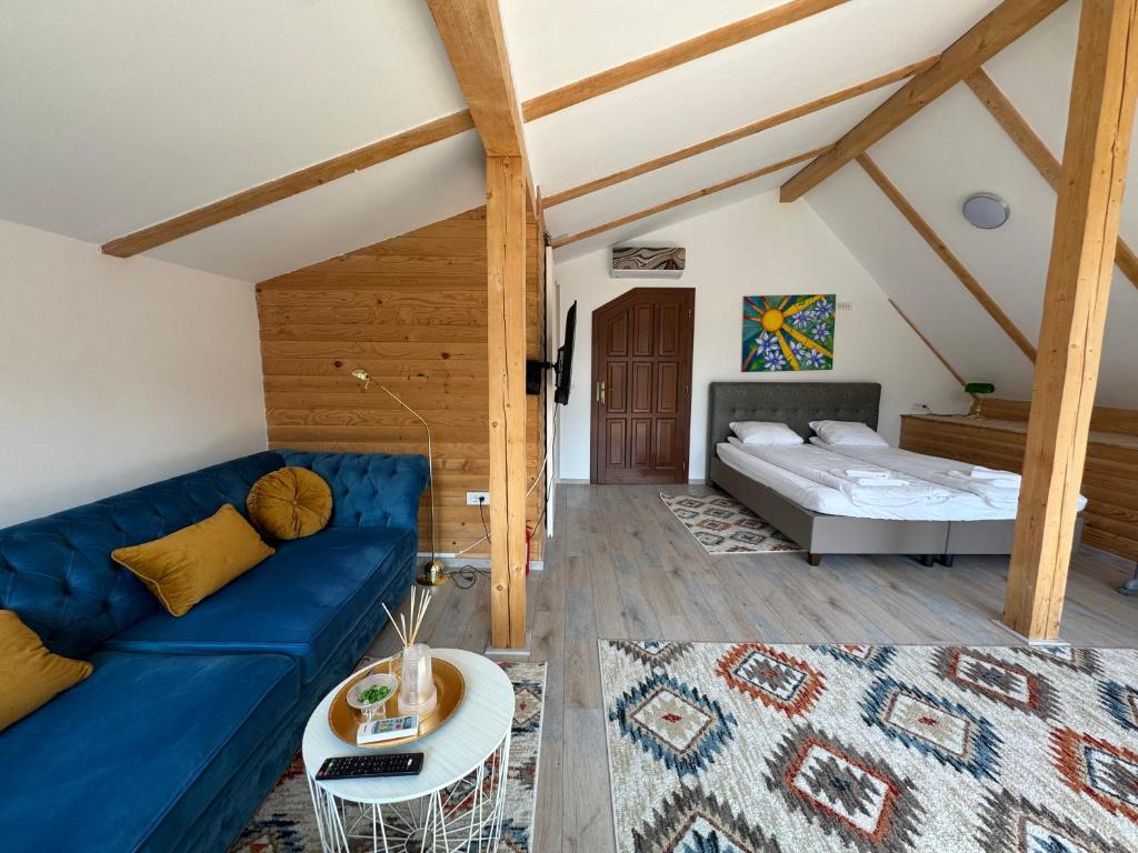 a living room with a blue couch and a bed at Vila Eruga - 3 stele in Poiana Mărului