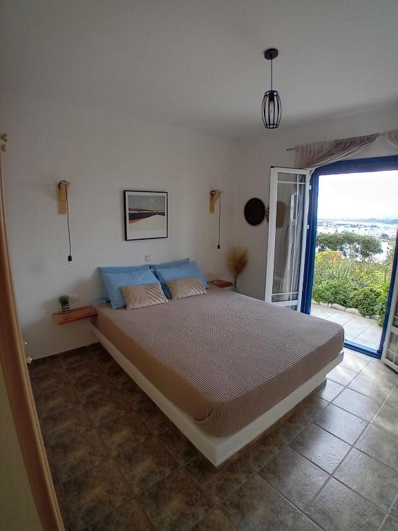 a bedroom with a large bed with a large window at Naxian Sofias garden in Naxos Chora
