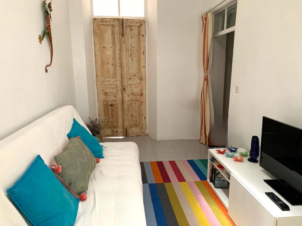 a living room with a white couch and a television at Casa Almirante Reis - Perfect Location & Rooftop in Olhão