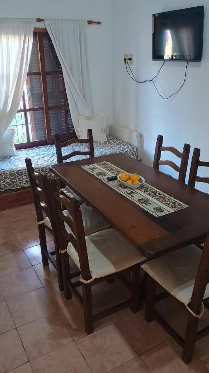 a wooden table with chairs and a plate of oranges on it at Las Gemelas 3 - Villa Elisa in Villa Elisa