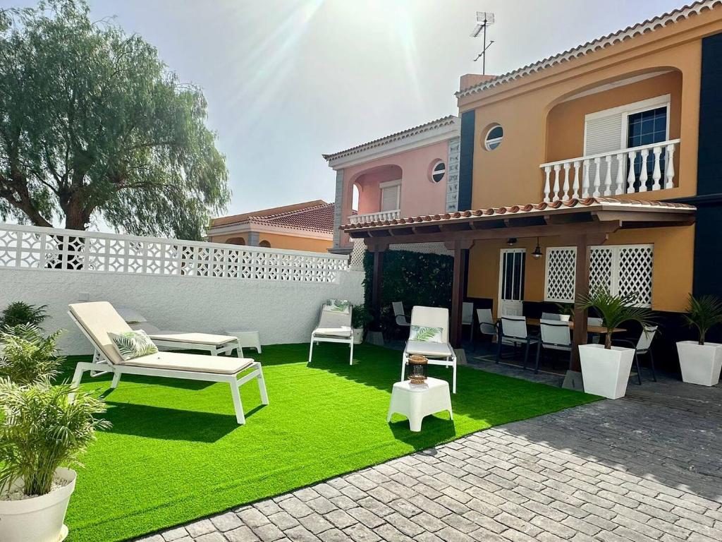 un cortile con prato verde e sedie e una casa di Casa Caletillas a Candelaria