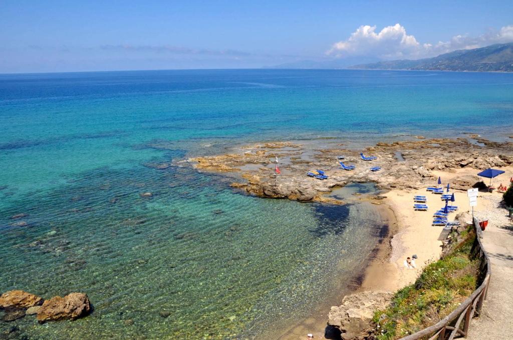 una playa con sillas y sombrillas y el océano en Residence del Mare, en Palinuro