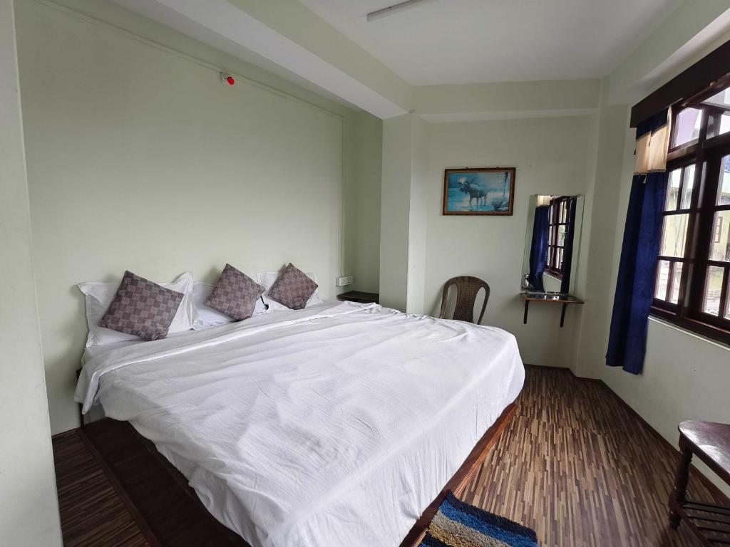 een slaapkamer met een groot wit bed in een kamer bij Hotel O Sun View in Gangtok