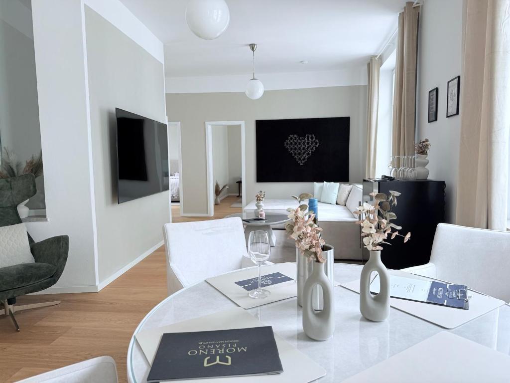 a white living room with a dining table with white chairs at designAparts - II - by MorenoPisano in Bayreuth