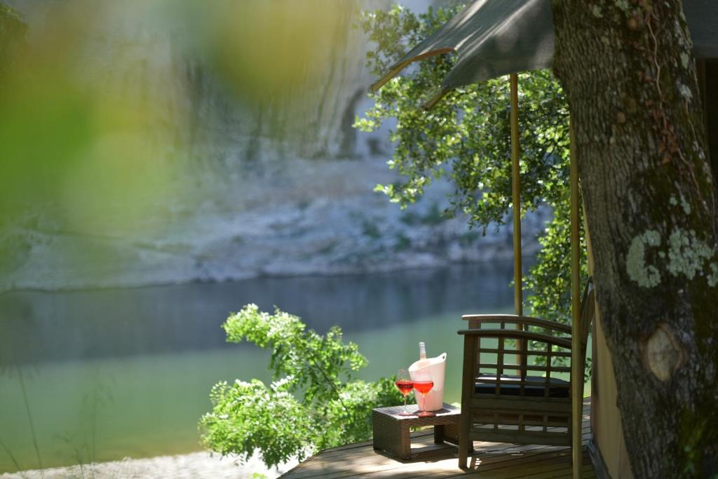 a table with a candle and an umbrella next to a river at Prehistoric Lodge in Vallon-Pont-dʼArc