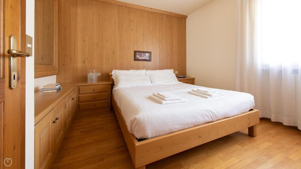 a bedroom with a bed with white sheets and wooden floors at Monte Solena 45C in Bormio