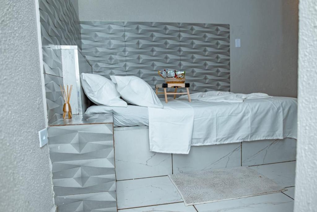 een bed met witte lakens en kussens in een kamer bij Alo viajante in Sorocaba