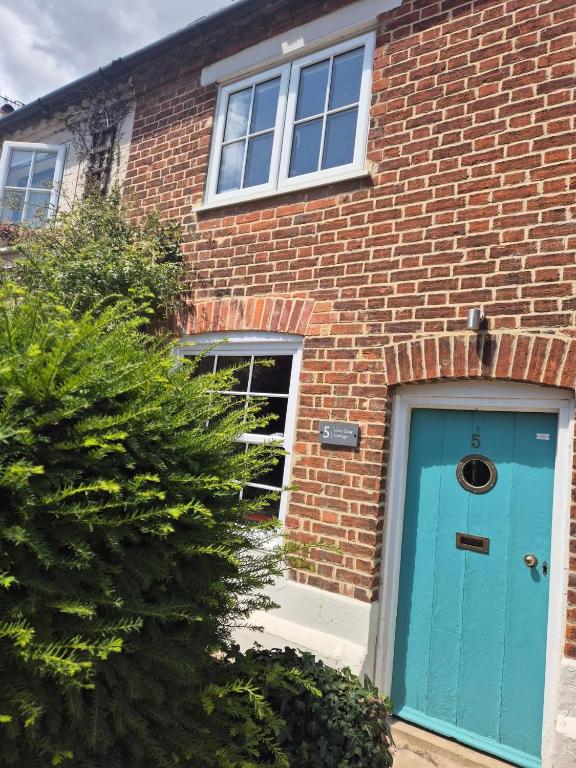 a brick house with a blue door at Lime Kiln Quay Cottage in Woodbridge