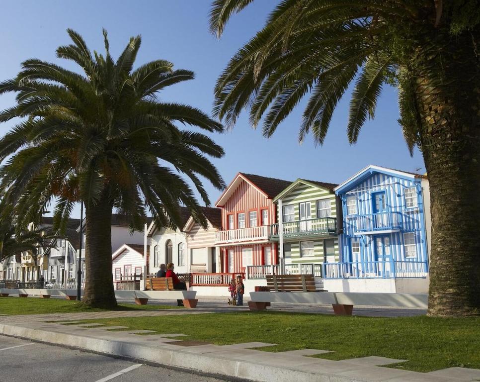 une rangée de maisons colorées dans une rue avec des palmiers dans l'établissement Beachfront Costa Nova Villa - 3 BR Apartment, à Gafanha da Encarnação