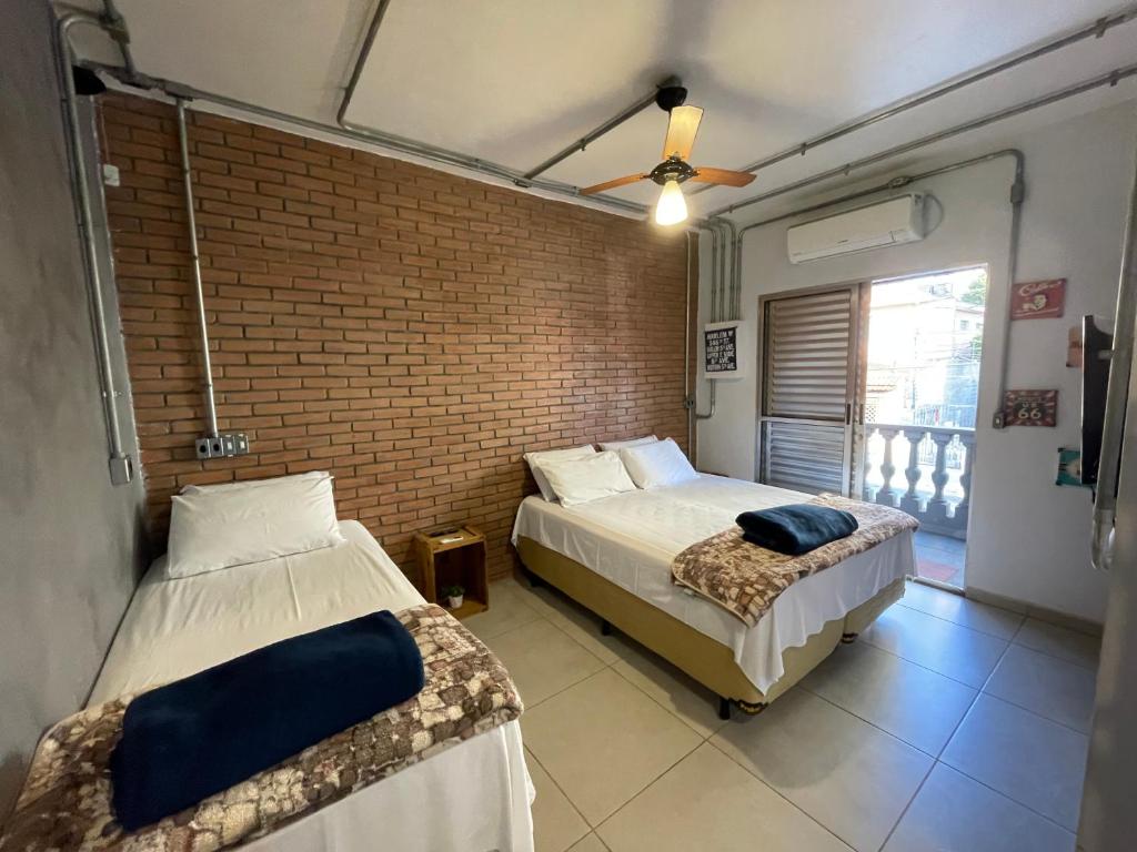 a bedroom with two beds and a brick wall at Studio House in Sao Paulo