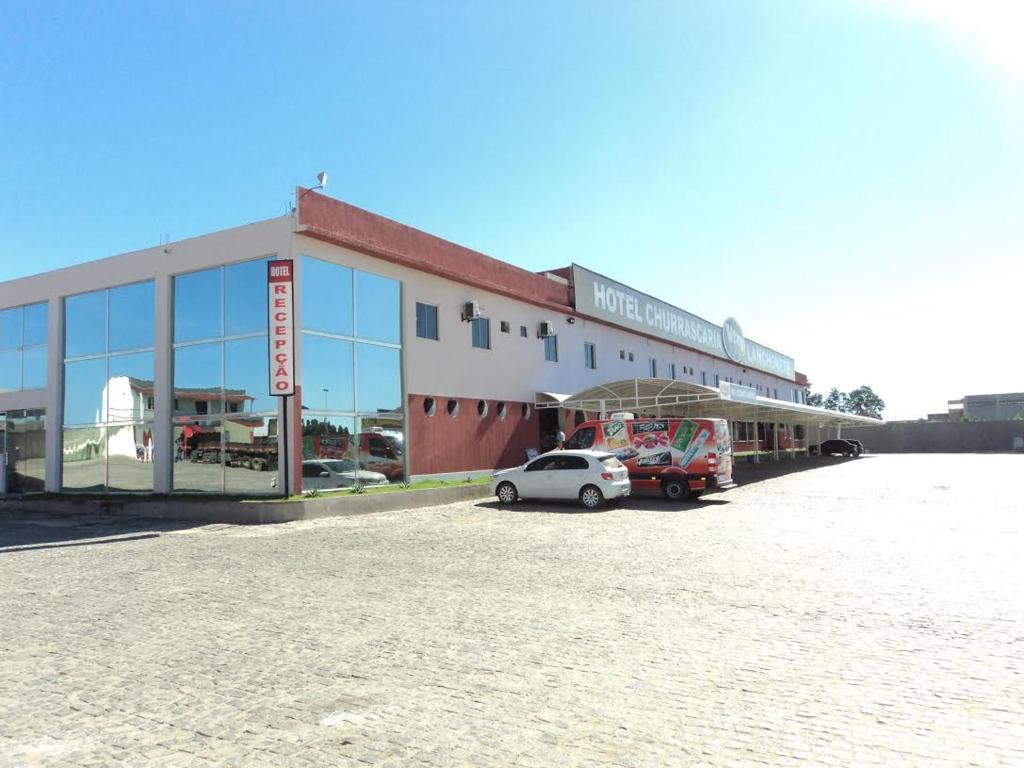 a building with a car parked in a parking lot at Hotel Vento Sul in Teixeira de Freitas