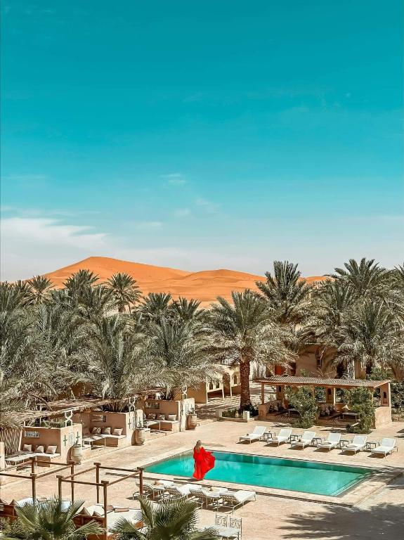 un hôtel dans le désert avec piscine et palmiers dans l'établissement Riad Serai Merzouga, à Merzouga