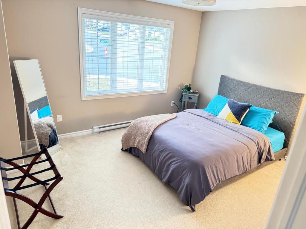 a bedroom with a bed with blue pillows and a window at The Urban Hideout in St. John's