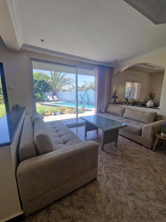 a living room with a couch and a table at Villa spacieuse avec piscine proche aéroport Mohamed V in Nouaseur