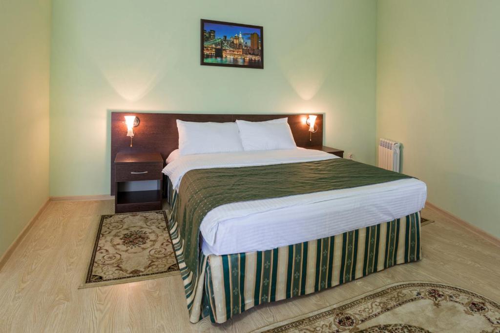 ein Schlafzimmer mit einem großen Bett und einer grünen Decke in der Unterkunft Hotel Viktorya in Stawropol