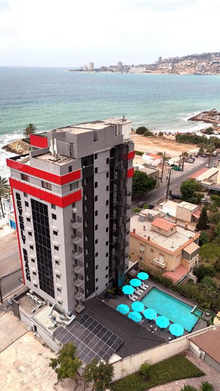 an aerial view of a building with a pool and the ocean at Beverly Beach Hotel in Jounieh