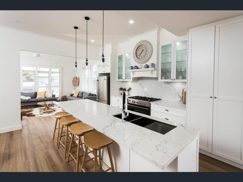 Una cocina blanca con encimera y taburetes. en Kyabram Happy House WIFI Pet Friendly, en Kyabram