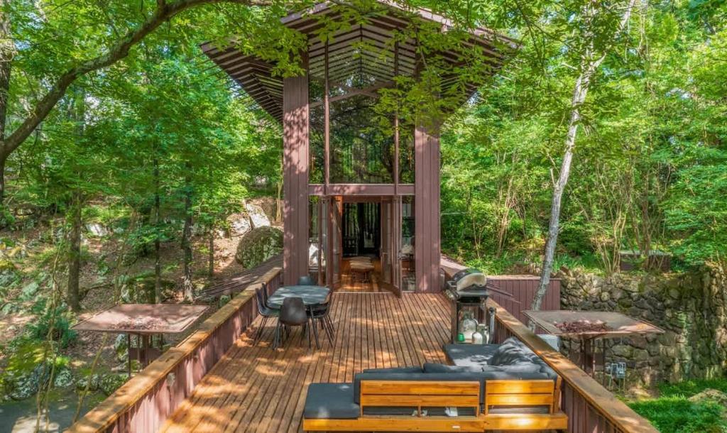 eine Holzterrasse mit einem Pavillon im Wald in der Unterkunft Stoneflower Cottage in Heber Springs