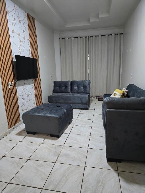 a living room with couches and a flat screen tv at Casa Sítio in Rio Verde