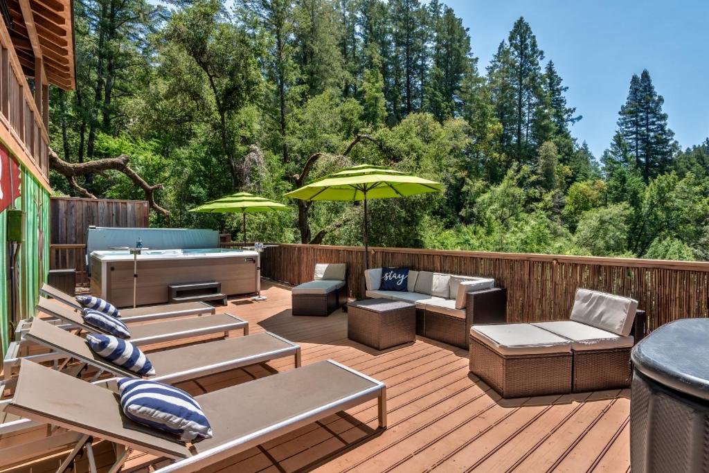 a deck with chairs and tables and an umbrella at Skyview Grove Cabin in Camp Meeker