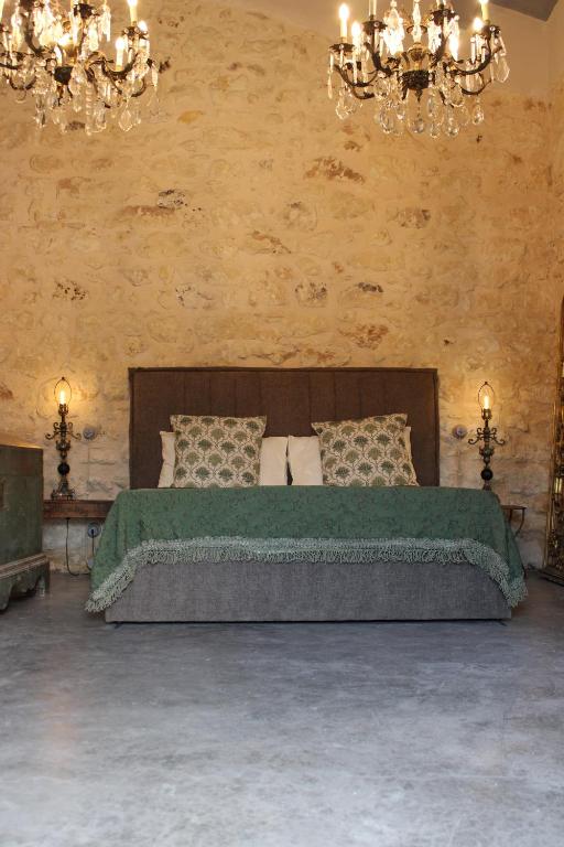 a bedroom with a large bed with a green blanket at Chiusa del prete 1867 in Noto