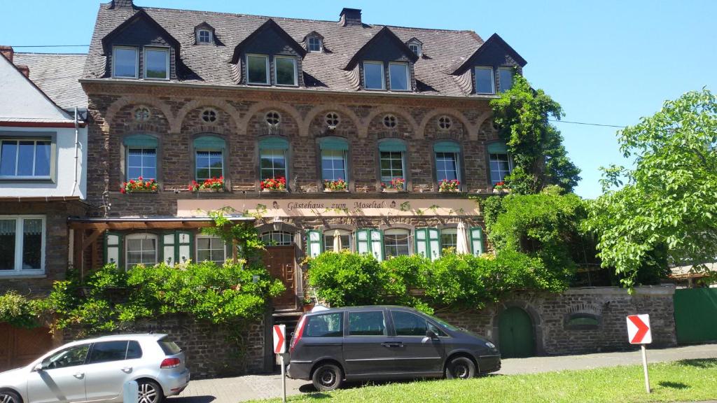 dos coches estacionados frente a un edificio en Gästehaus zum Moseltal, en Ellenz-Poltersdorf